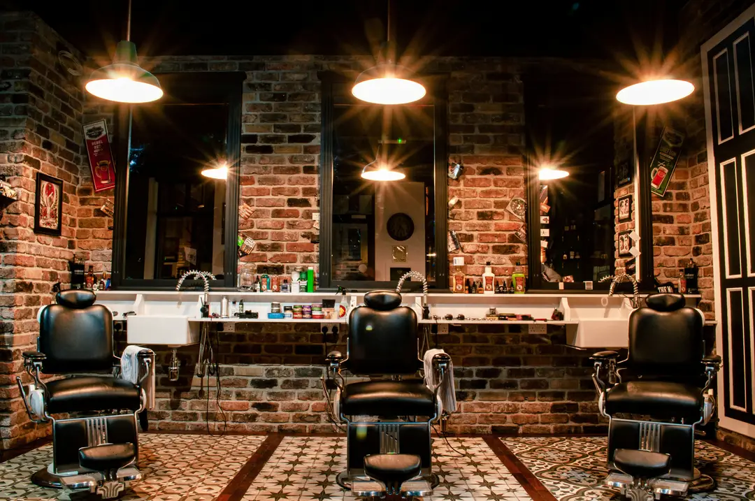 Barbería con sillones de cuero negro y muro de ladrillo